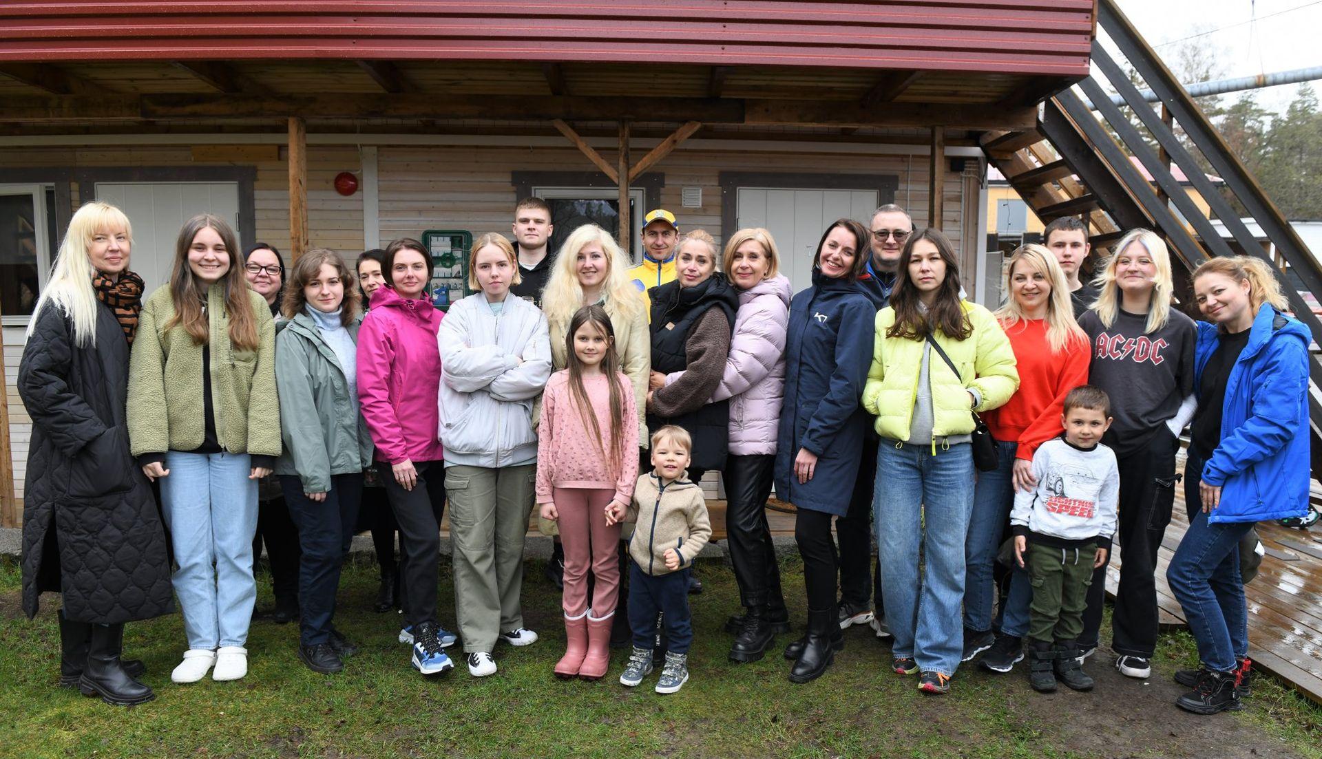 Group of people posing together outside a building with wooden stairs on a cloudy day.